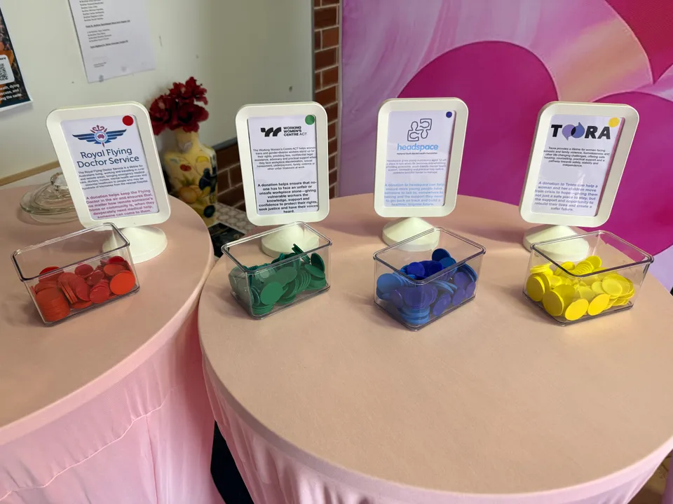 Four labelled charity collection jars on the pink welcome desk.