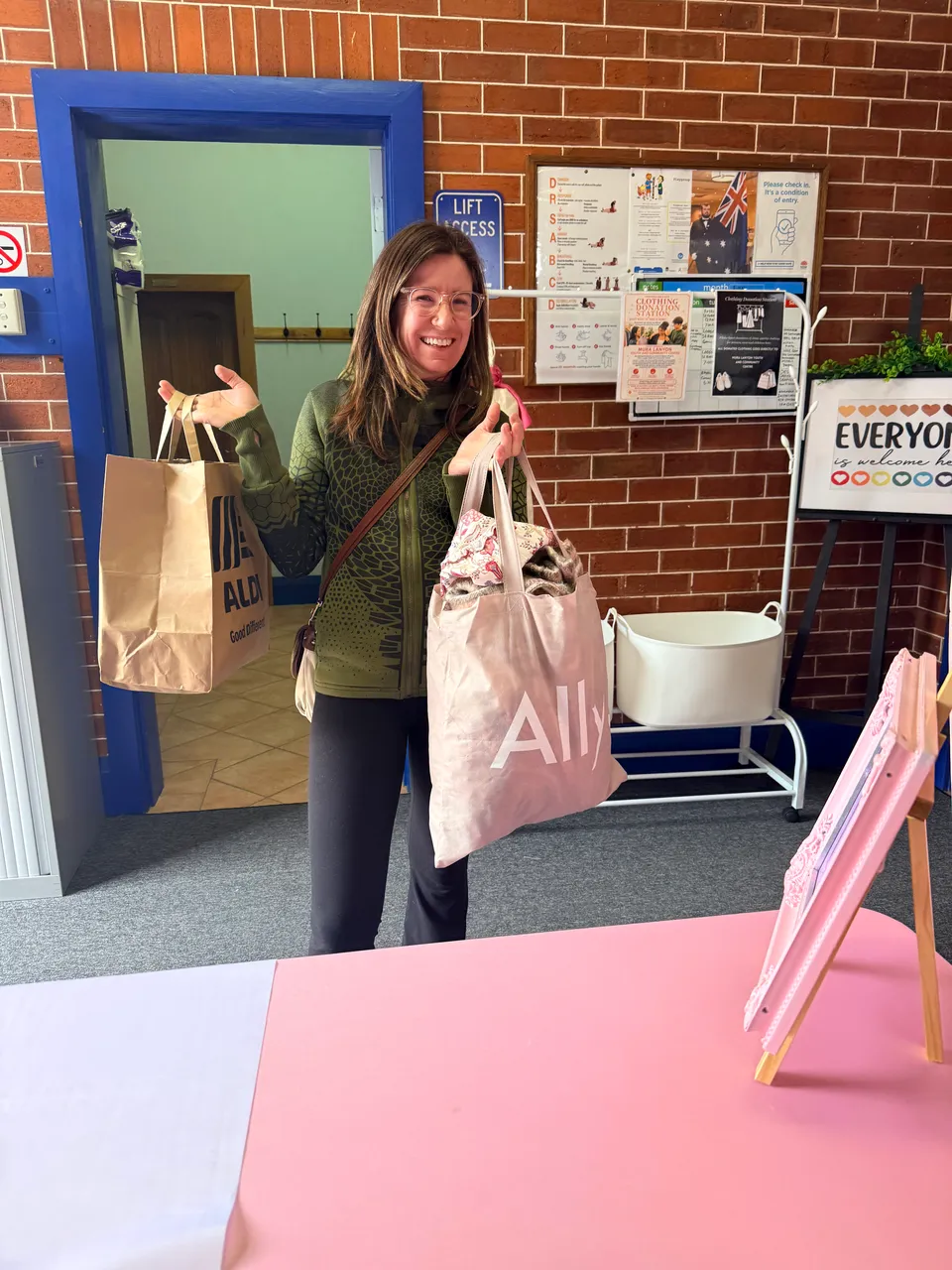A smiling shopper holding bags of market finds by the entrance.